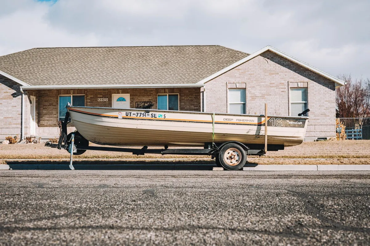 Fishing boat on its trailer parked in front of a house