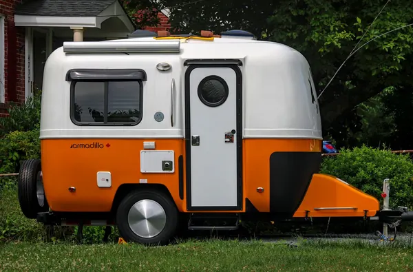 A small camper trailer parked on the grass in a suburban yard