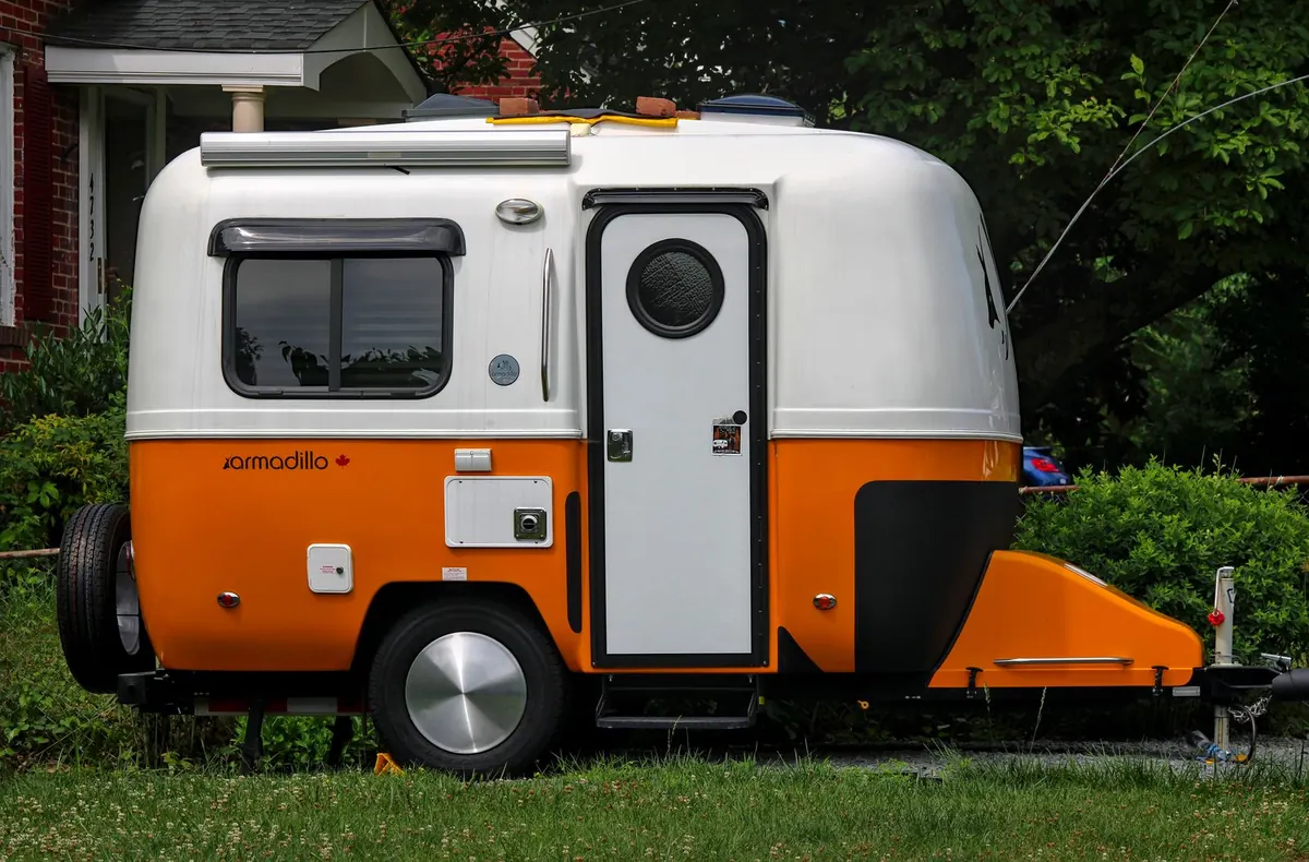 Small camper trailer parked on the grass in a suburban yard