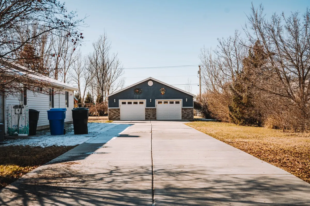 Long concrete driveway leading to a detached two-door garage