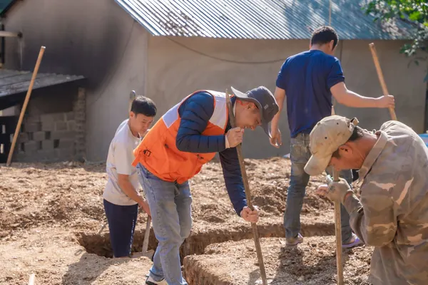 Workers digging a foundation footing trench by hand