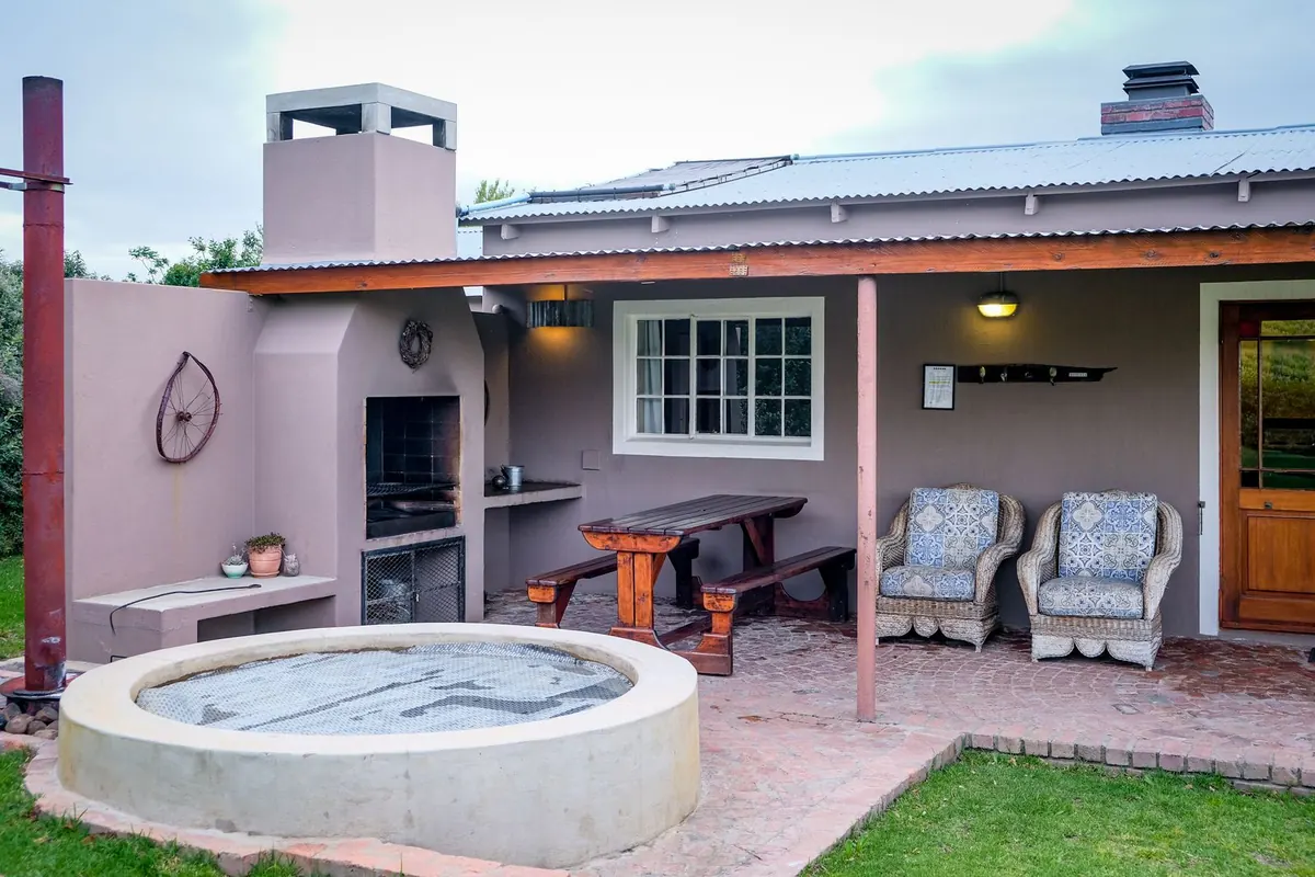 Round hot tub set on a concrete patio beside a covered outdoor kitchen