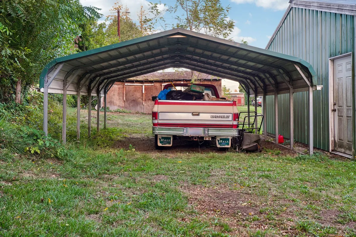 Pickup truck parked on grass under a metal carport
