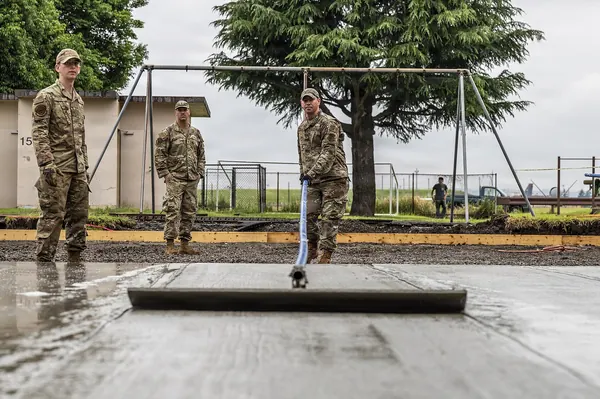 U.S. Air National Guard civil engineers striking off a concrete pad with a screed board