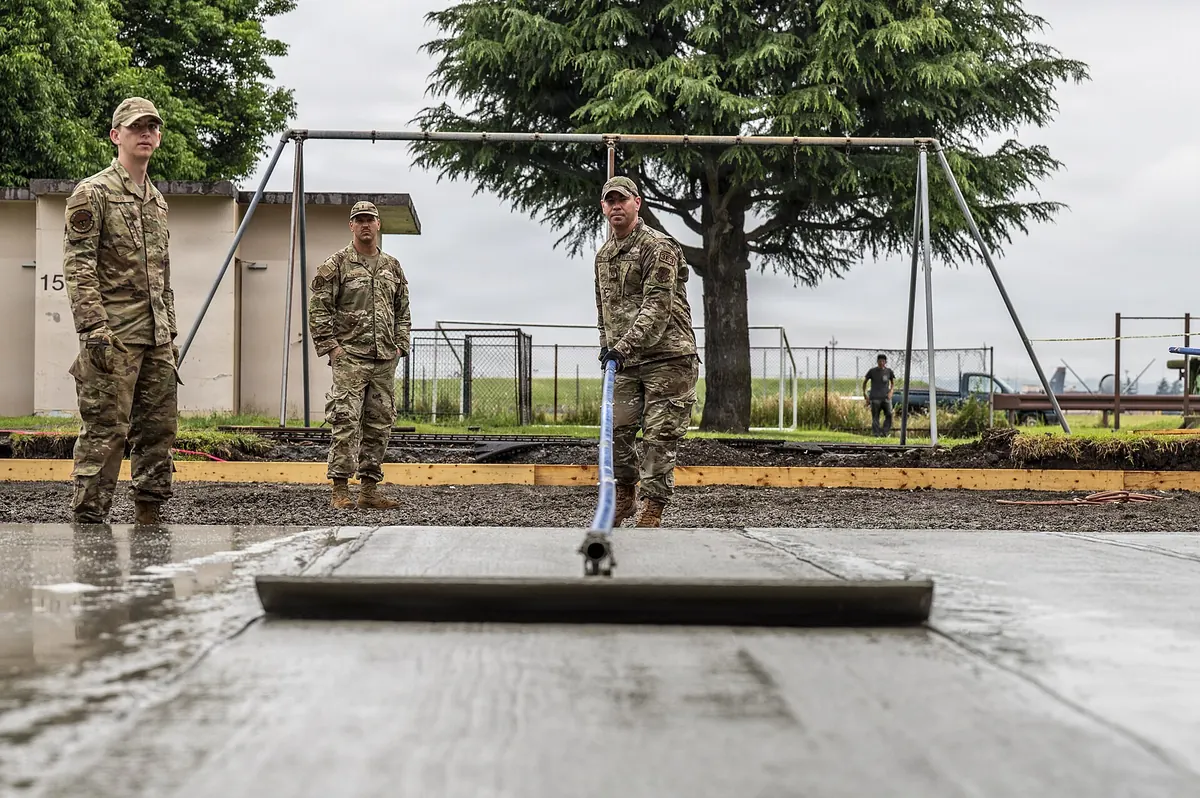 Civil engineers striking off a concrete pad with a screed board