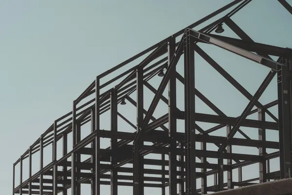 Steel frame of a metal building going up against a pale sky