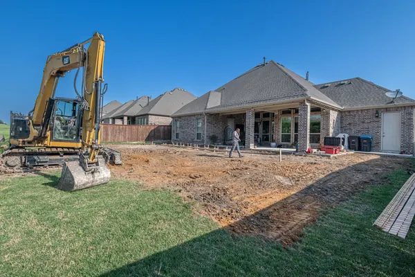 An excavator grading a Texas backyard for a new patio