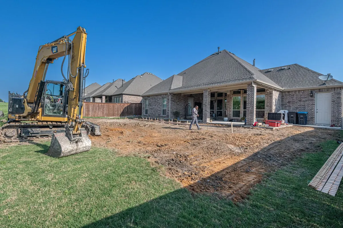 Excavator grading a Texas backyard for a new patio