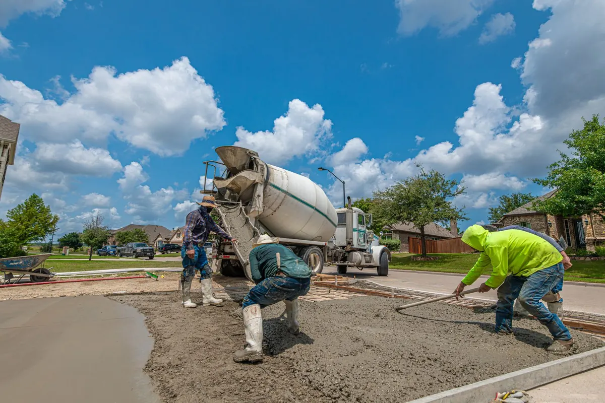 Crew spreading concrete from a mixer truck for a driveway in Fort Worth, Texas